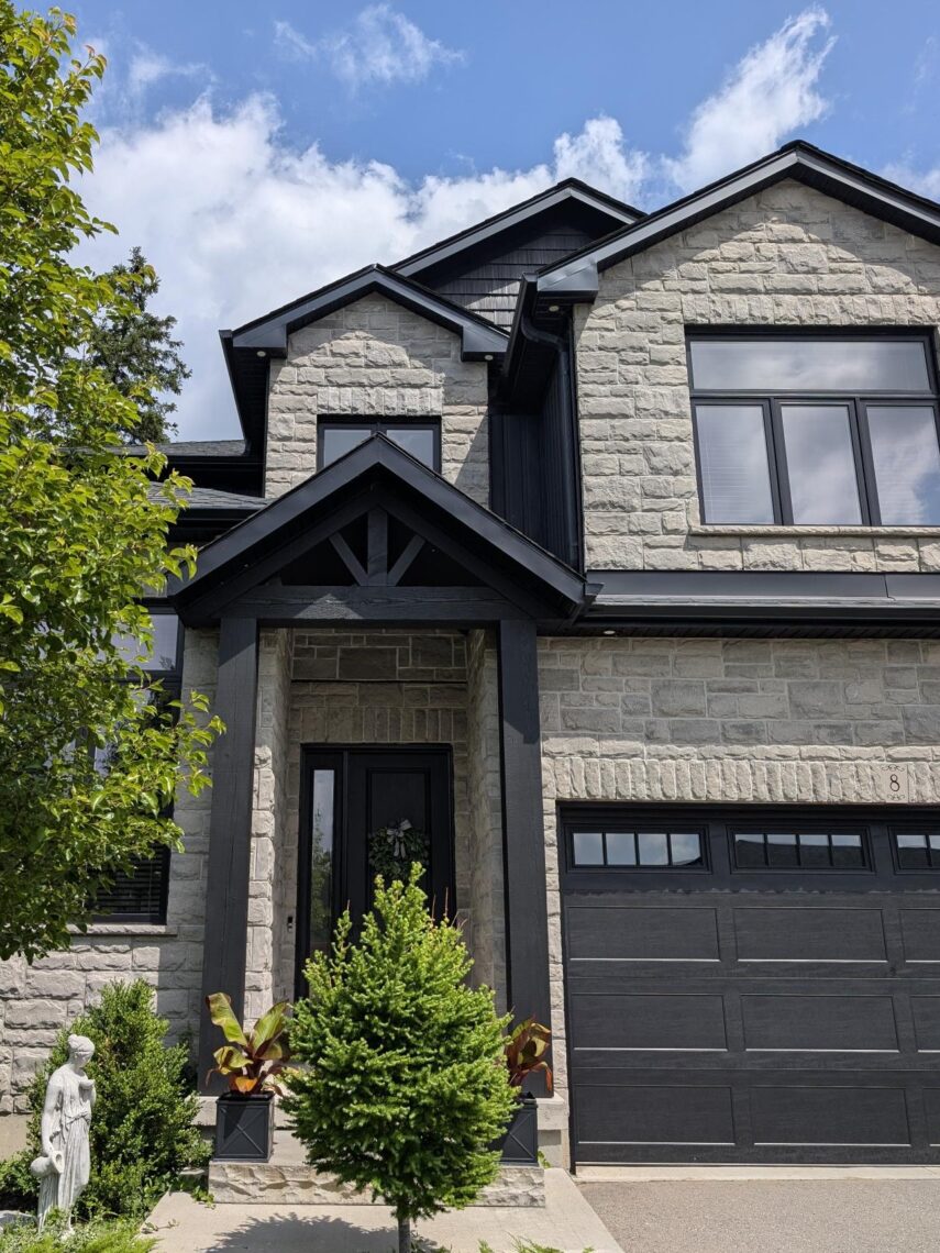 Completed timber-frame entry with stone facade and black trim on a Kitchener home